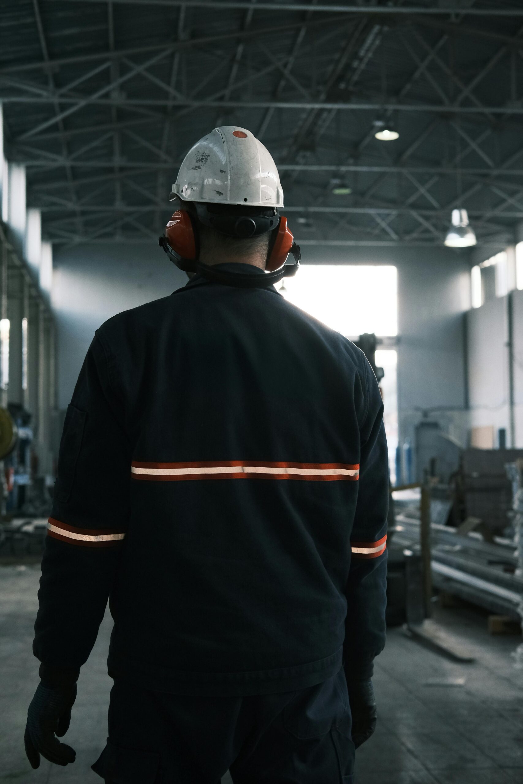 IATF 16949 Training - Industrial worker in safety gear walking in factory with back to camera