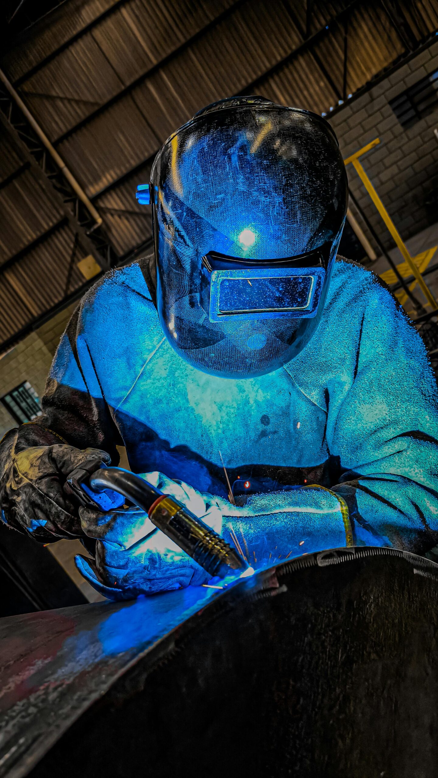 IATF 16949 auditor training - Welder in blue welding in a dark room