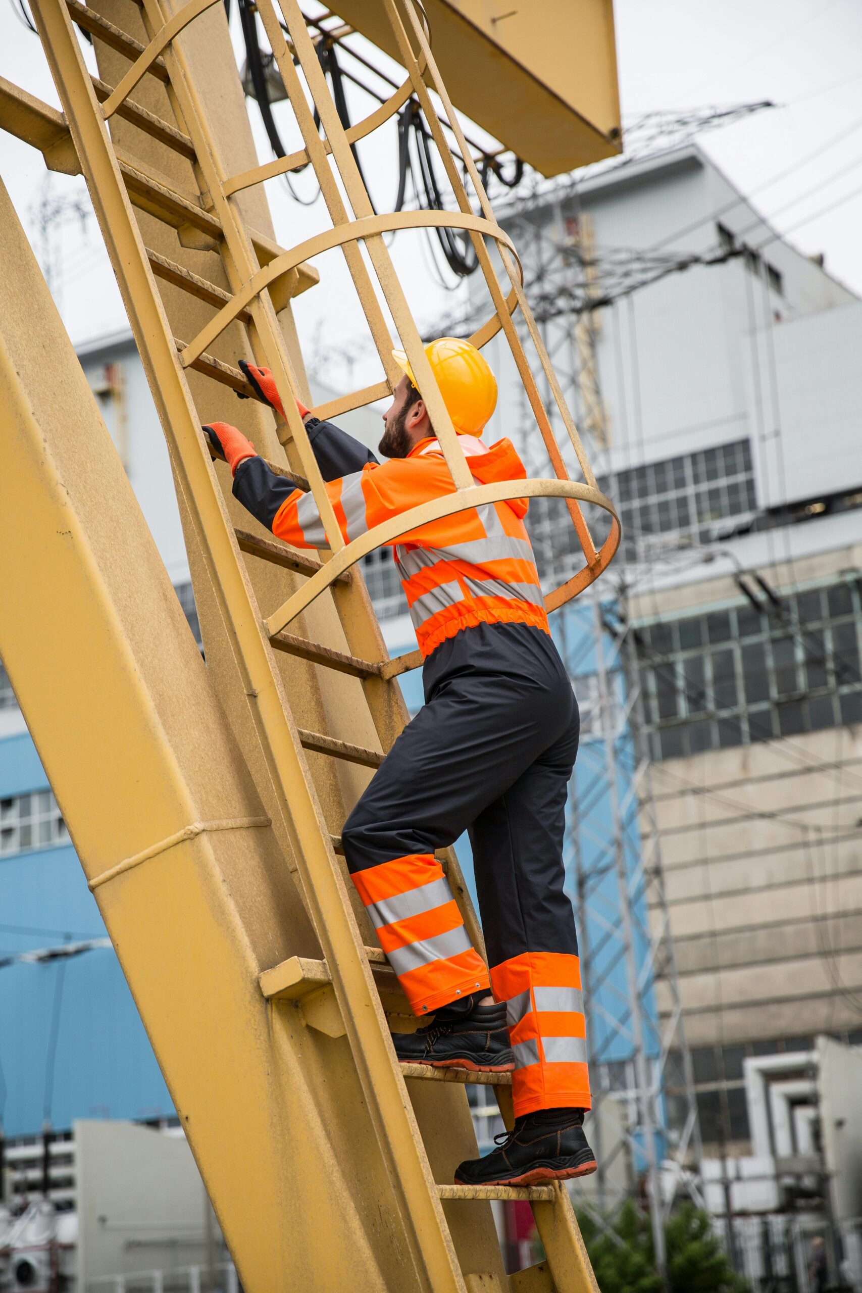 ISO 45001 Internal Auditor Training - Man wearing reflective orange pants and jacket climbing a ladder